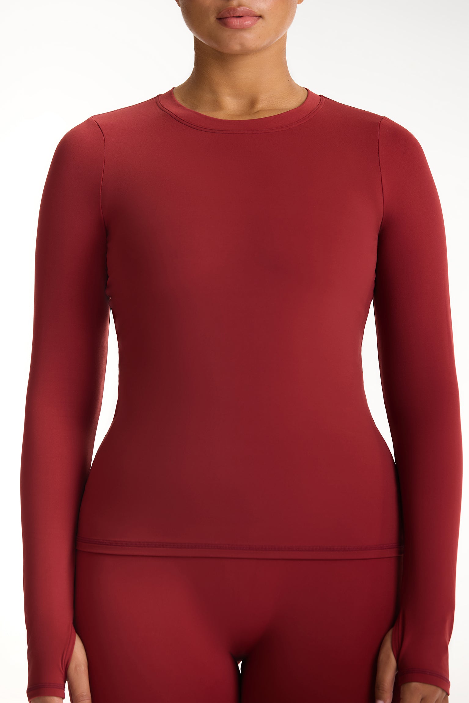 Red long-sleeve top worn by a person on a white background