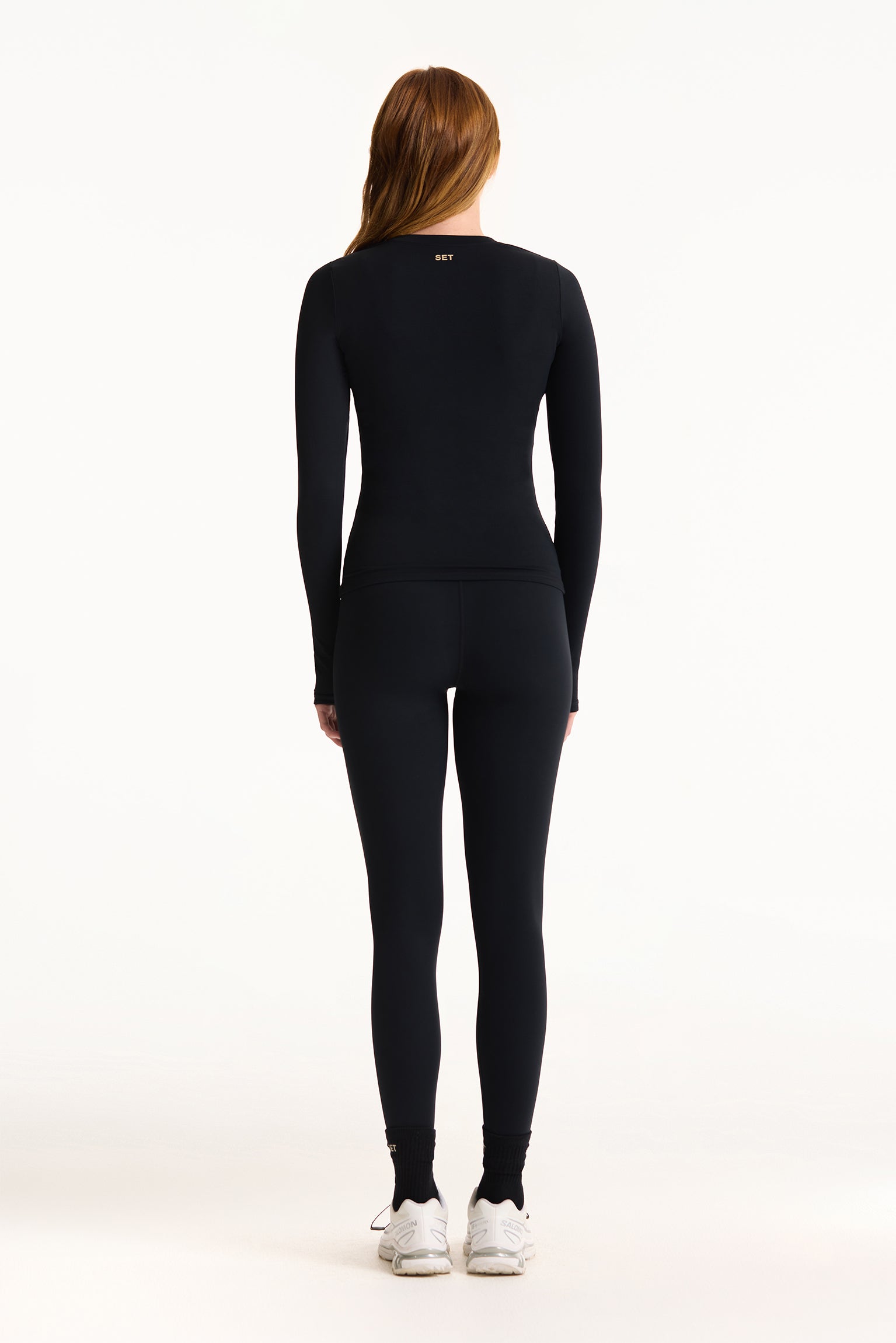 Person wearing a black long-sleeve top and leggings on a white background