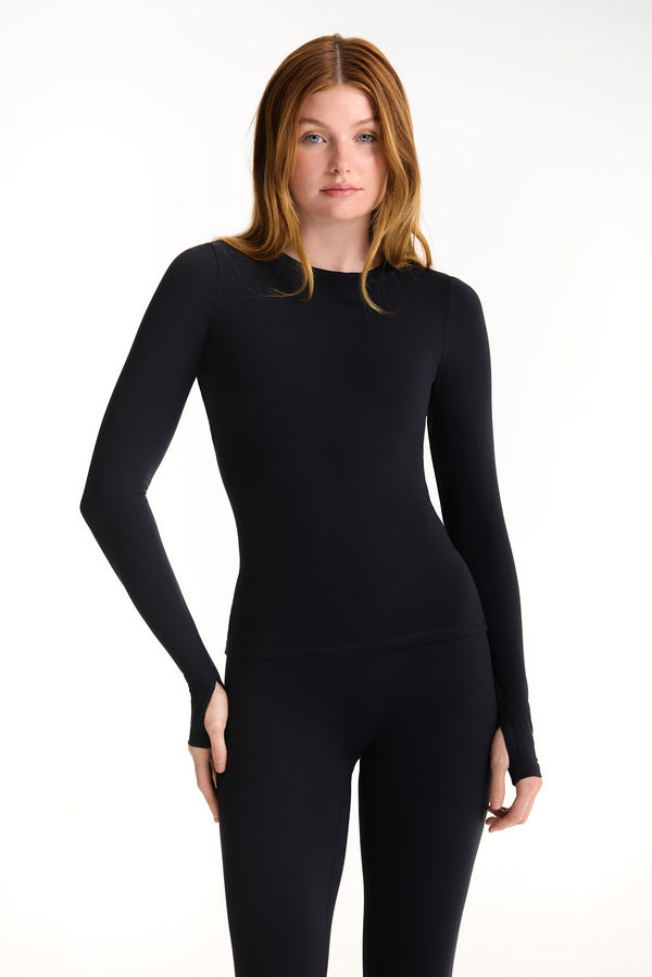 Woman wearing a black long-sleeve bodysuit on a white background