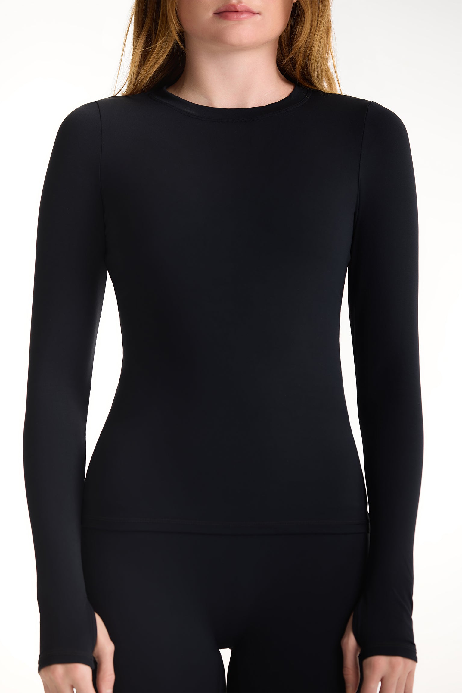 Black long-sleeve top worn by a person on a white background