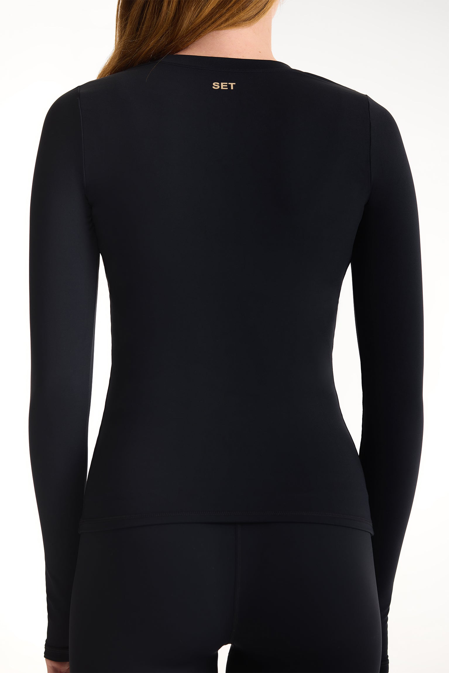 Black long-sleeve athletic top with 'SET' branding on the back, worn by a person.