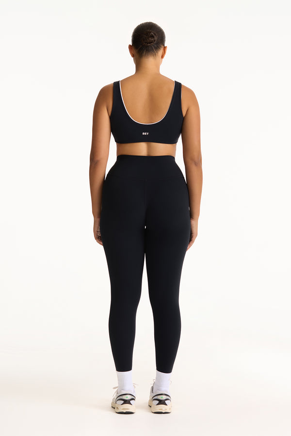 Person wearing a black sports bra and leggings set on a white background