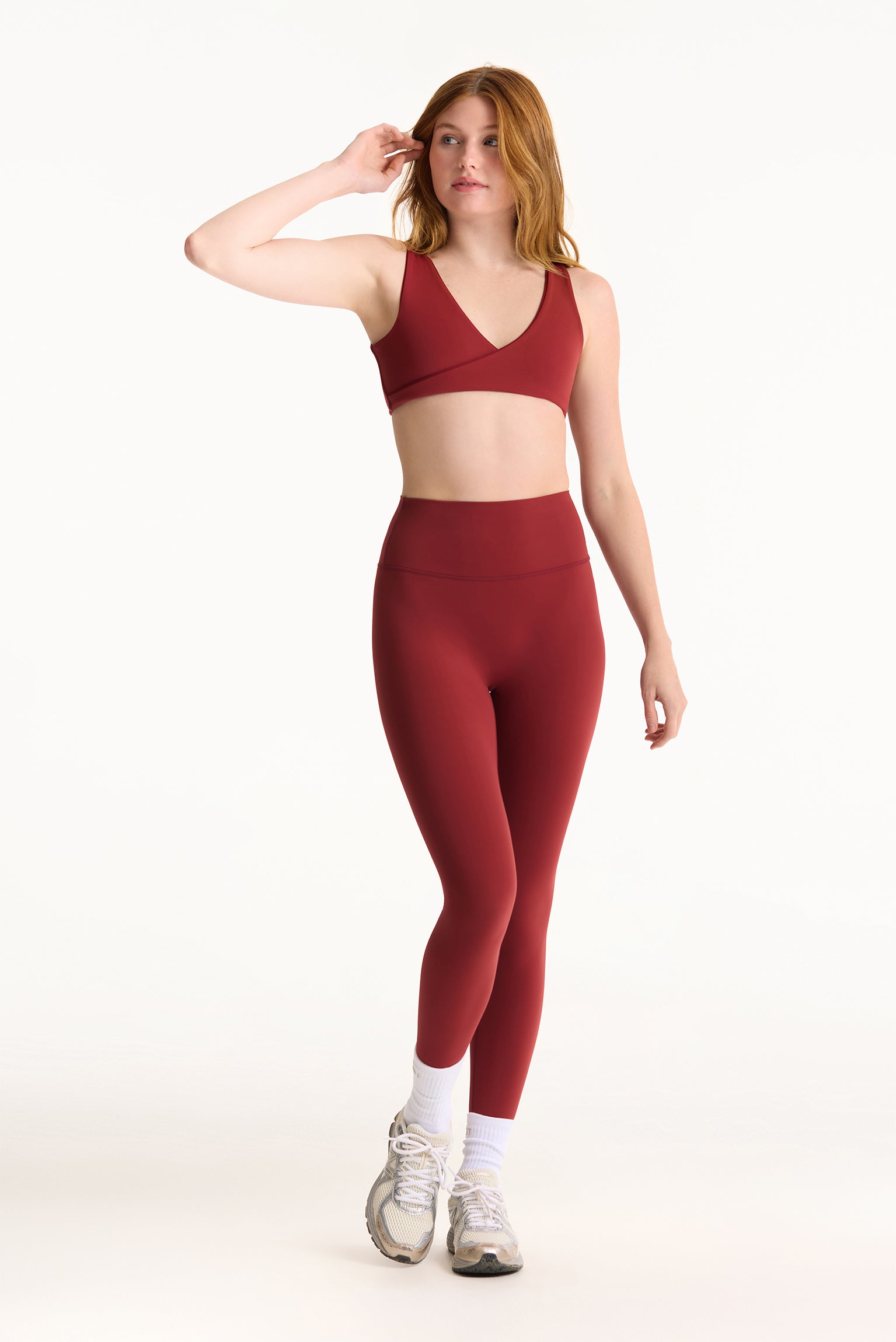 Woman wearing a red sports bra and leggings set on a white background