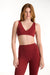 Woman wearing a red sports bra and leggings set on a white background <model-info>Dickey wears a size S and is 5’9”, 24” waist, 32” bust.</model-info>