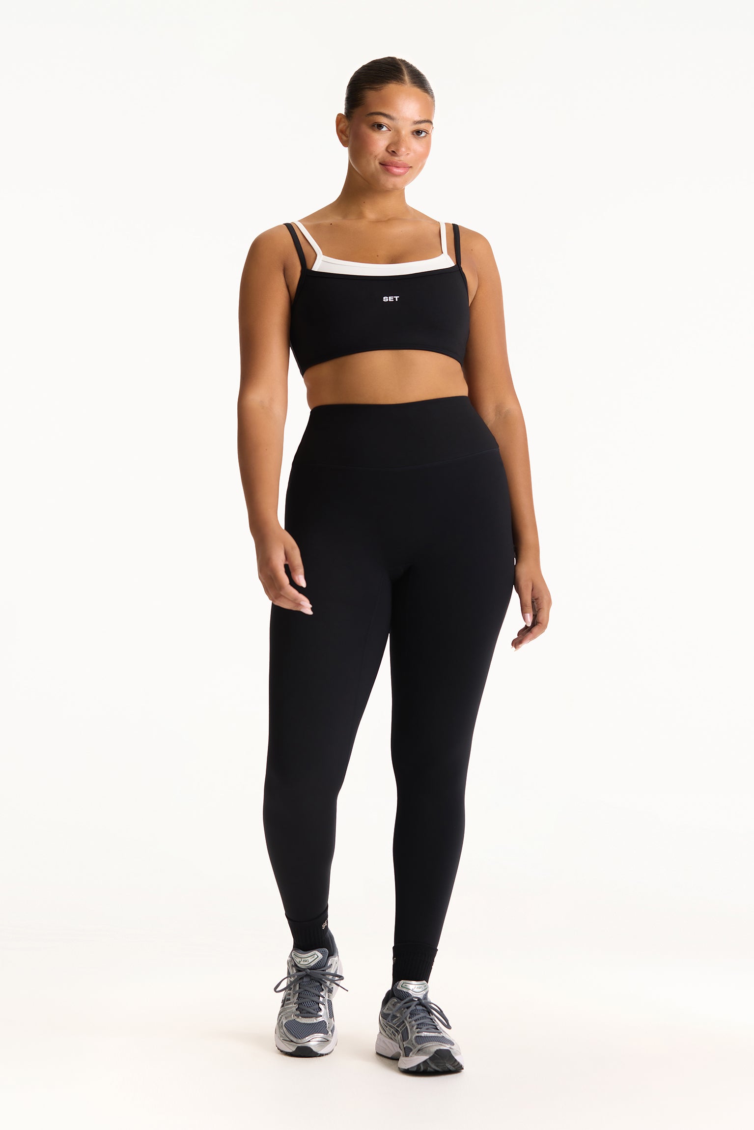 Woman wearing a black sports bra and leggings on a white background