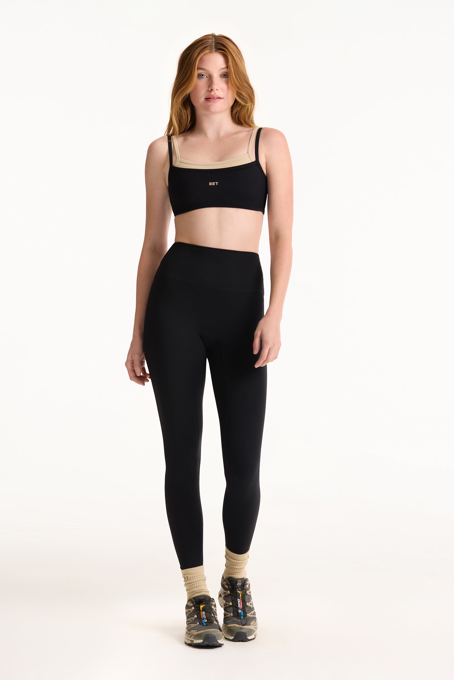 Woman wearing a black sports bra and leggings on a white background
