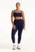 Woman wearing a navy sports bra and leggings set on a white background