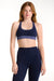 Woman wearing a navy sports bra and leggings on a white background <model-info>Dickey wears a size S and is 5’9”, 24” waist, 32” bust.</model-info>