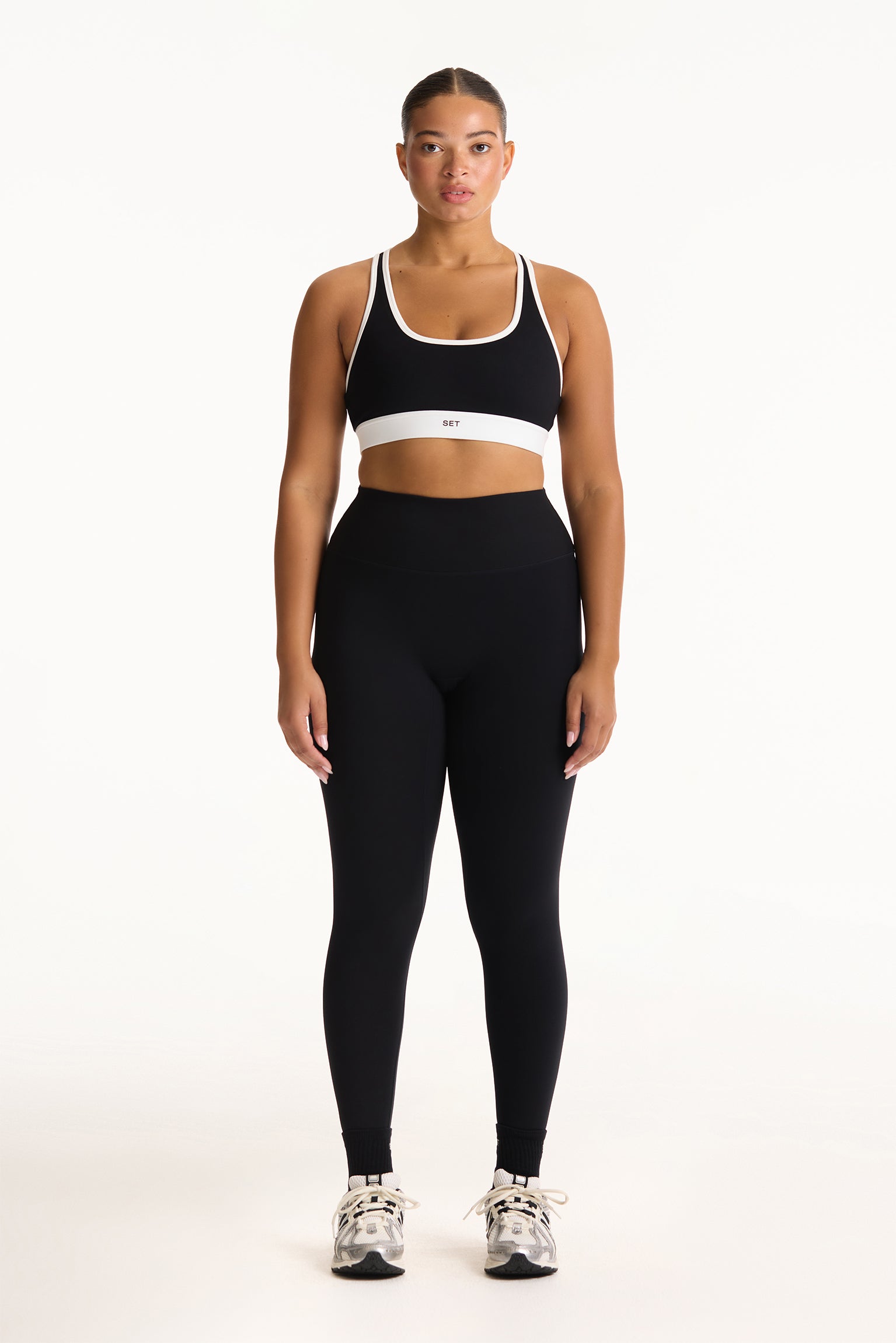 Woman wearing a black sports bra and leggings set on a white background