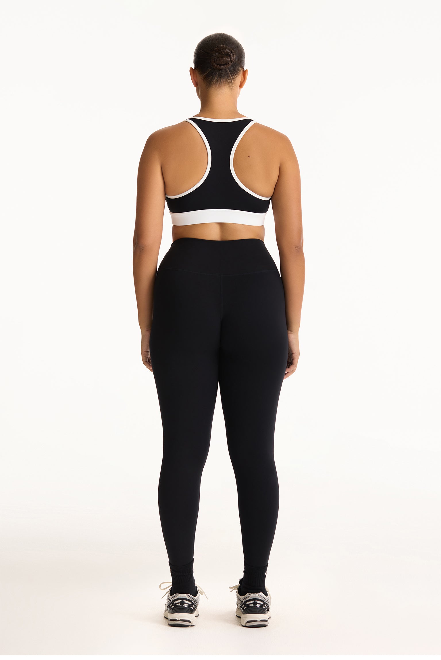 Person wearing a black sports bra and leggings set on a white background
