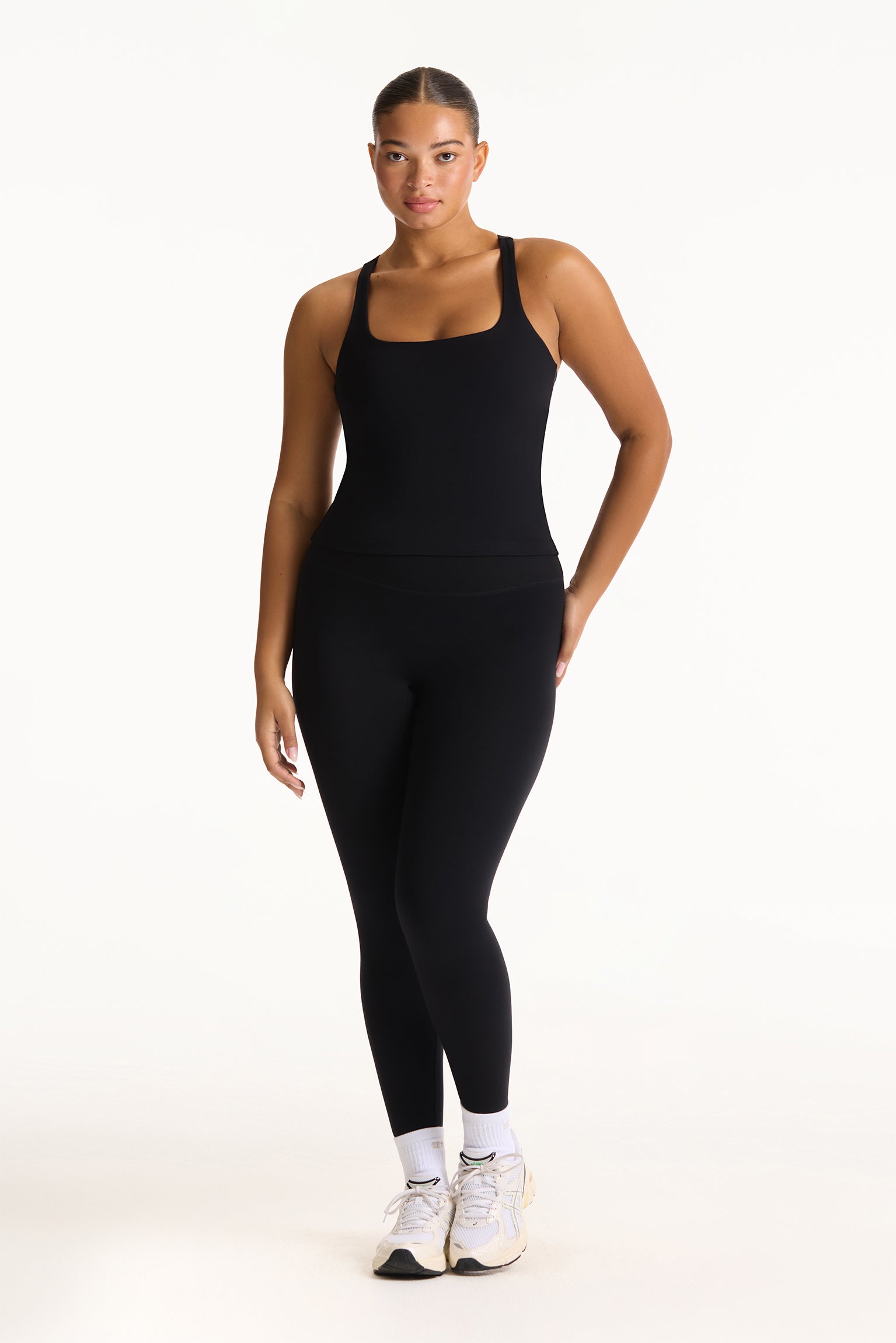 Woman wearing a black bodysuit on a white background