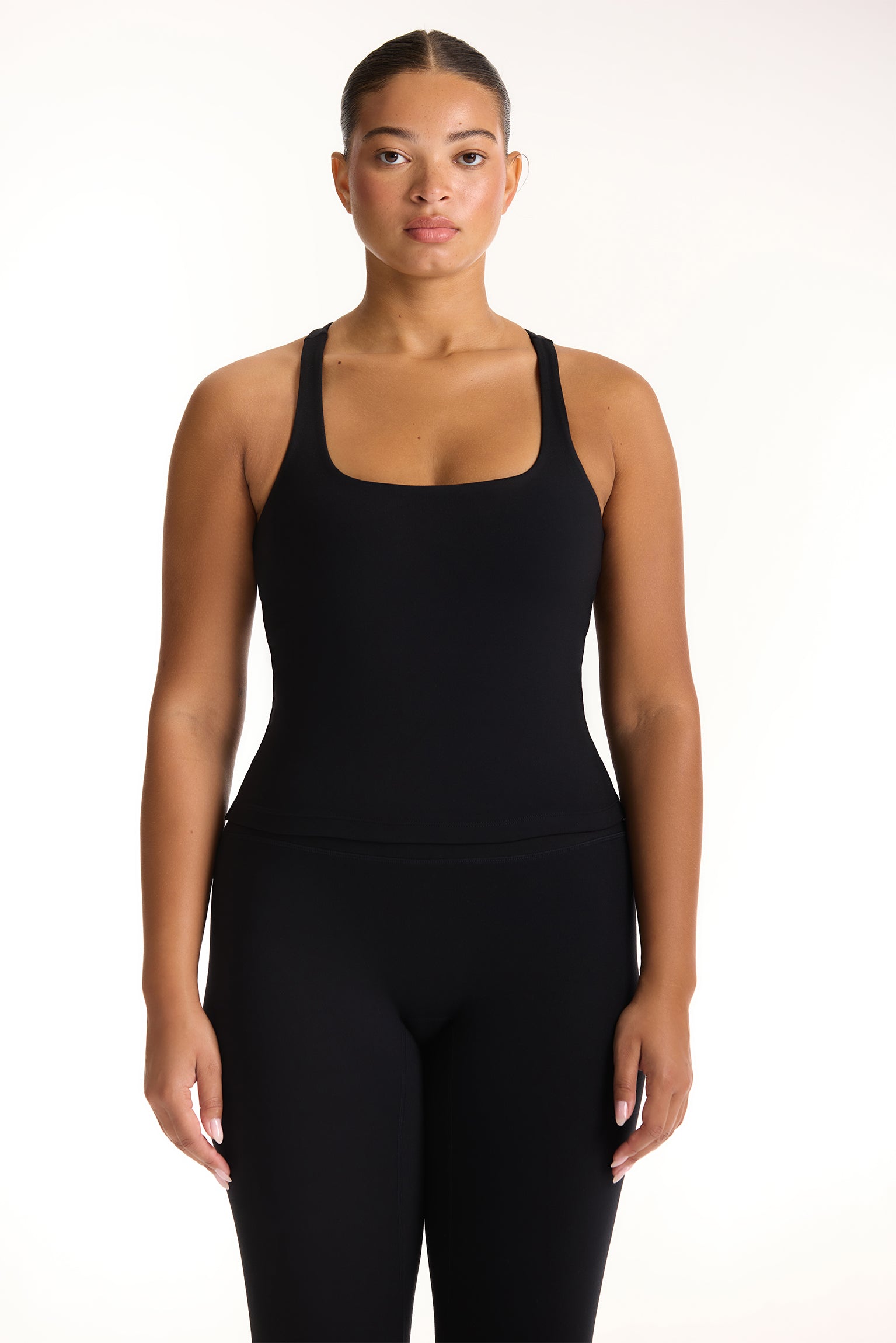 Woman wearing a black tank top and leggings on a white background <model-info>Jade wears a size L and is 5’9”, 30” waist, 38” bust.</model-info>