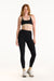 Woman wearing a black sports bra and leggings on a white background