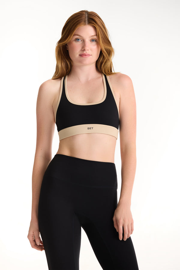 Woman wearing a black sports bra and leggings on a white background 