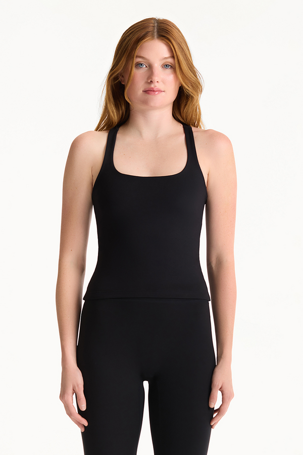 Woman wearing a black tank top and leggings on a white background