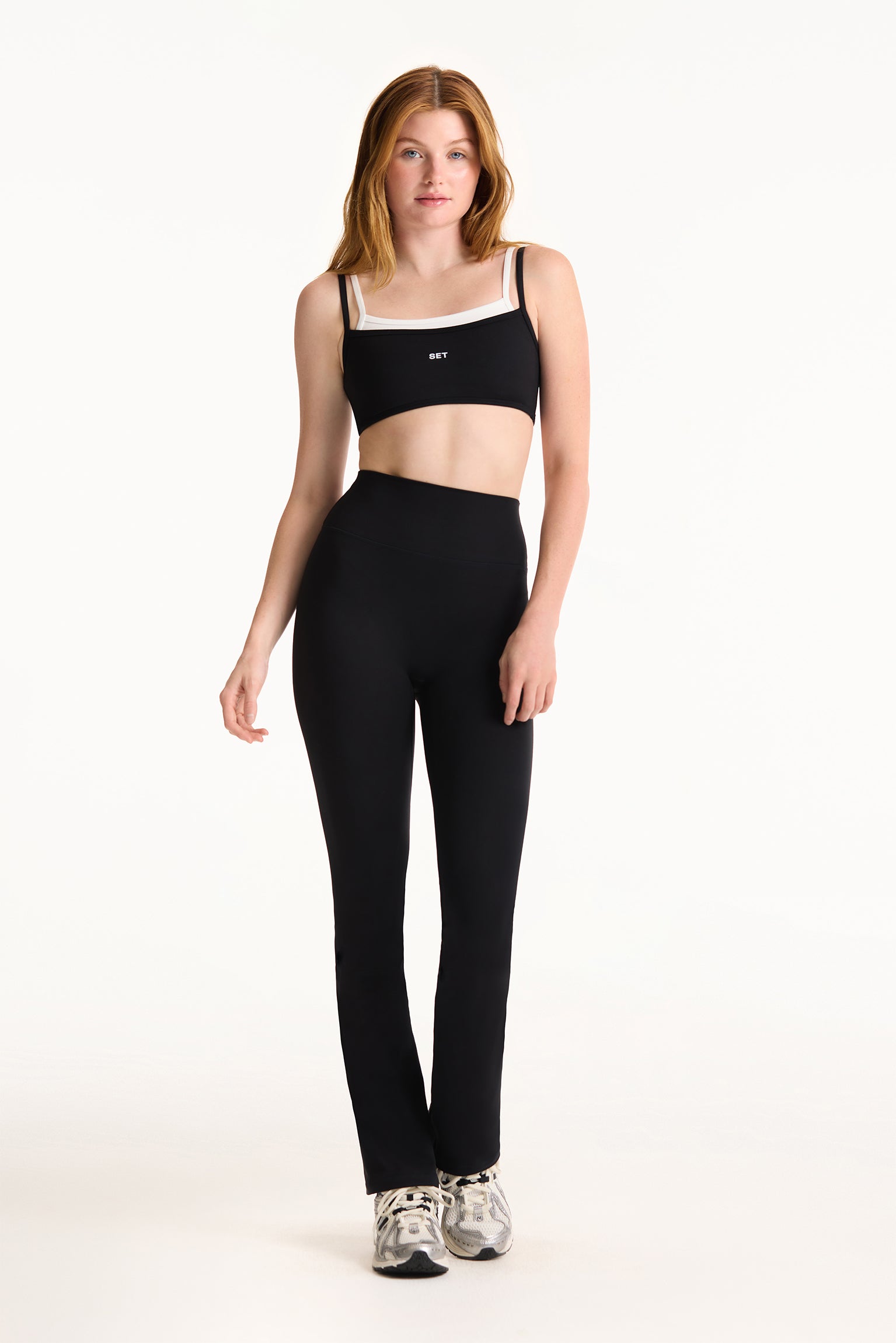 Woman wearing a black sports bra and leggings on a white background