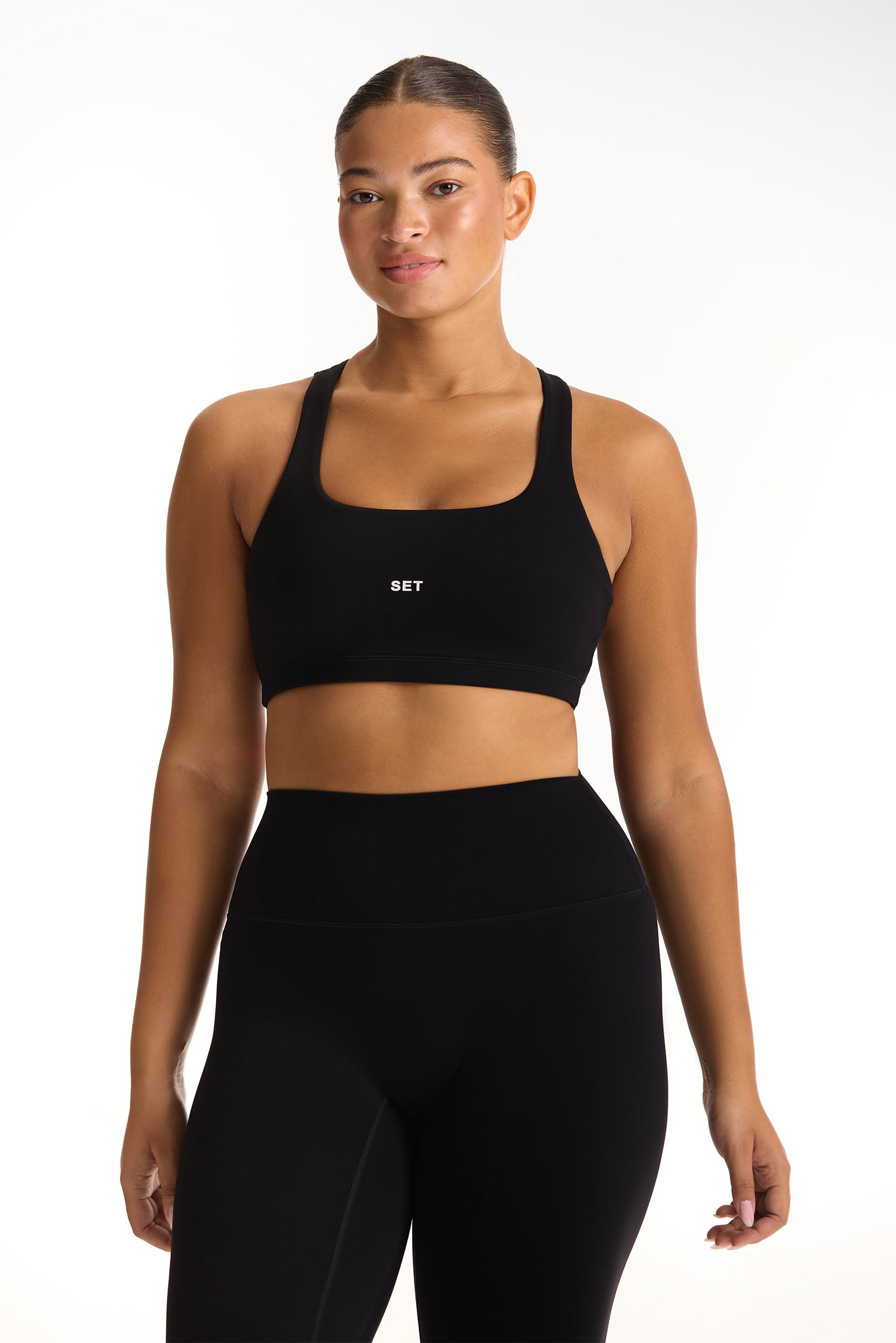Woman wearing a black sports bra and leggings with 'SET' branding on a white background <model-info>Jade wears a size L and is 5’9”, 30” waist, 38” bust.</model-info>