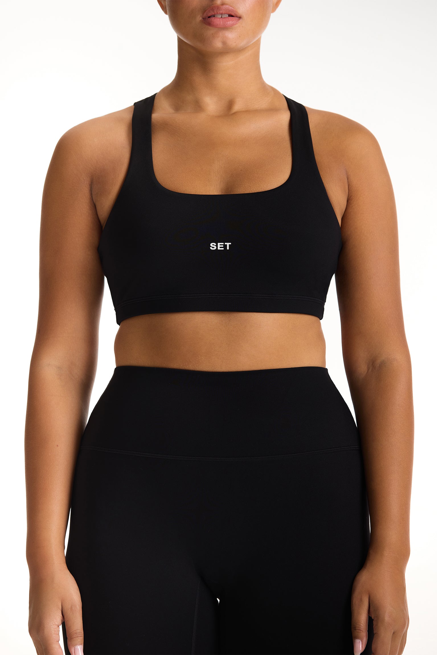 Black sports bra with 'SET' logo worn by a person on a white background