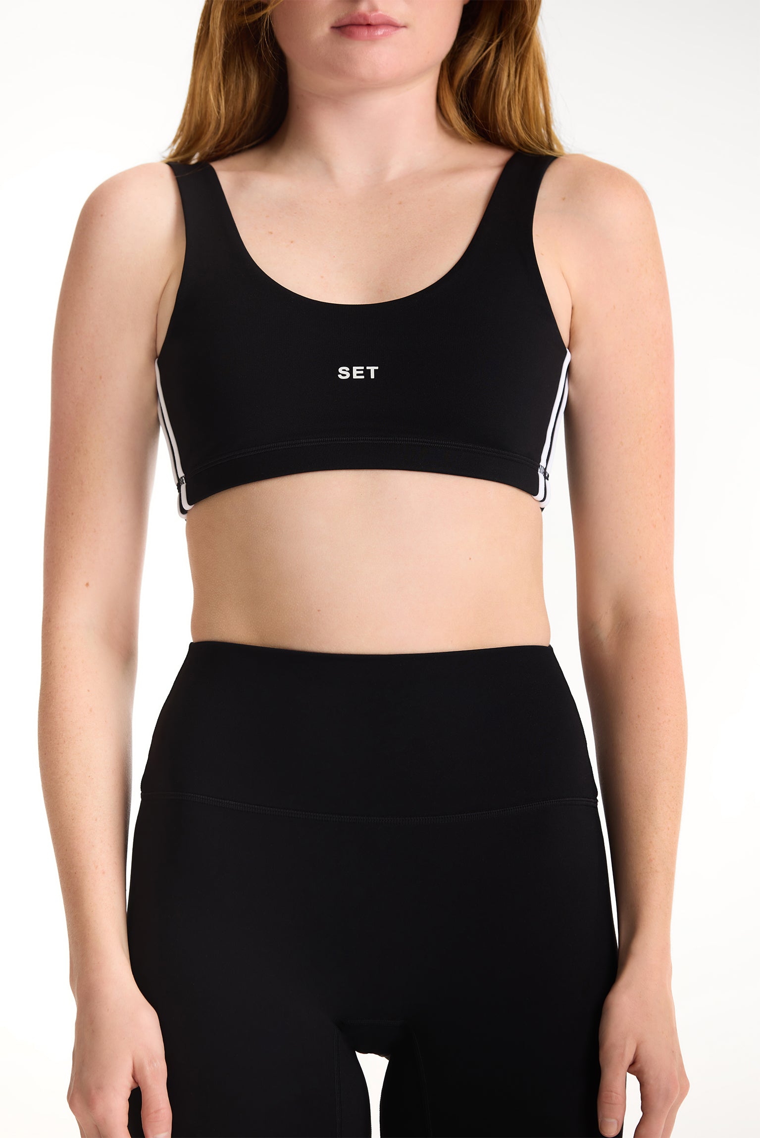 Black sports bra with 'SET' logo worn by a person on a white background