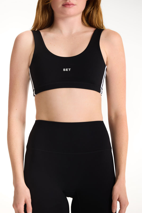 Black sports bra with 'SET' logo worn by a person on a white background