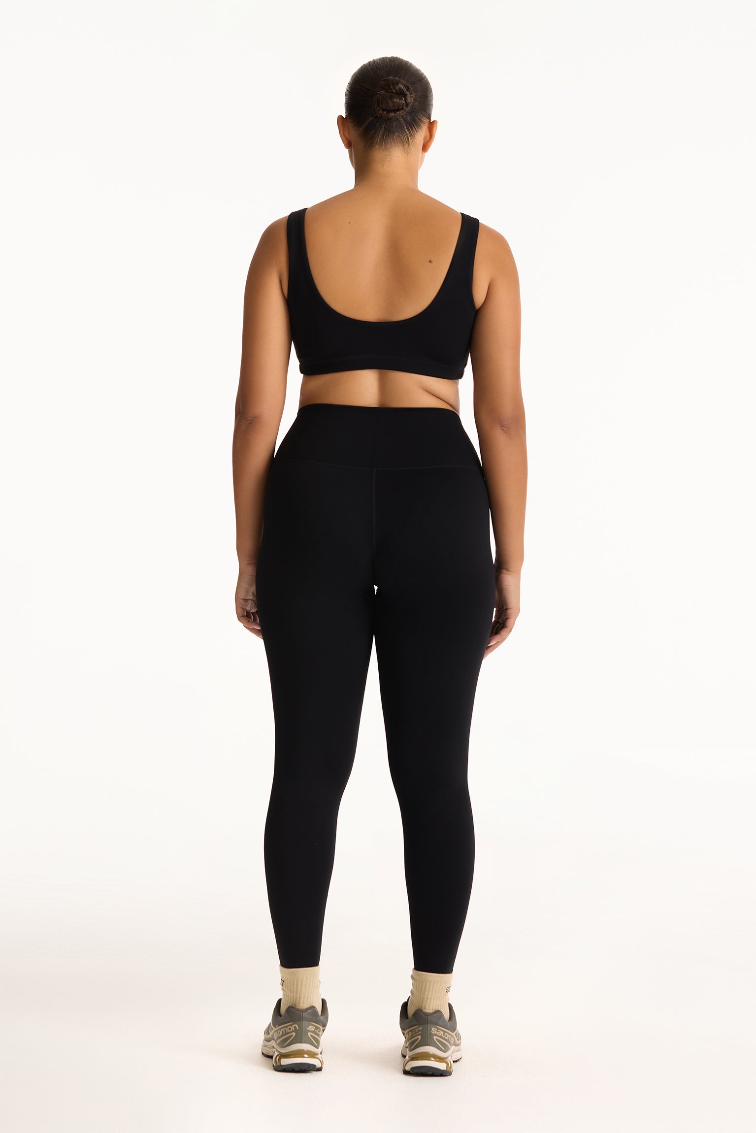 Person wearing a black sports bra and leggings set on a white background