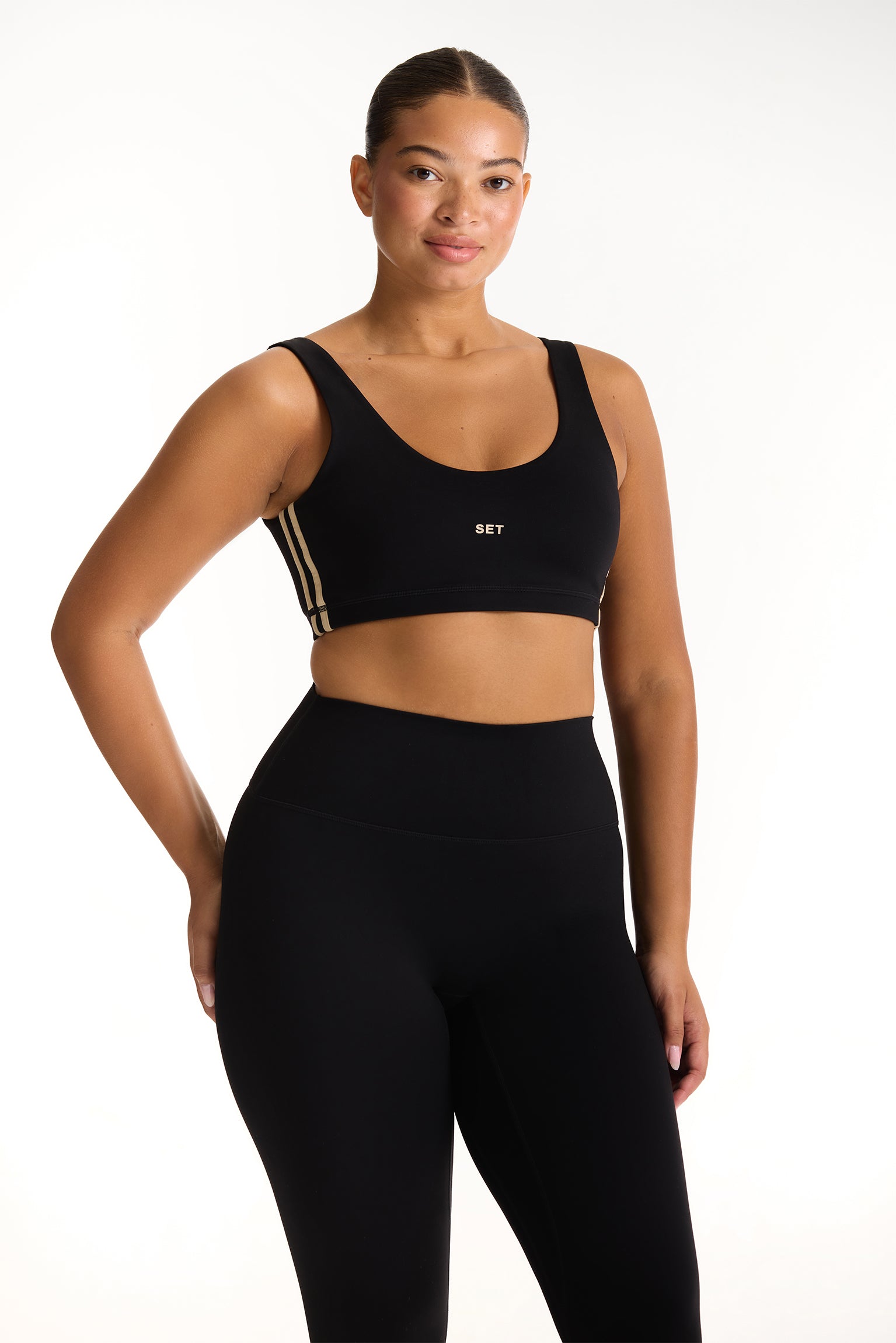 Woman wearing a black sports bra and leggings with a white background 