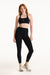 Woman wearing a black sports bra and leggings on a white background