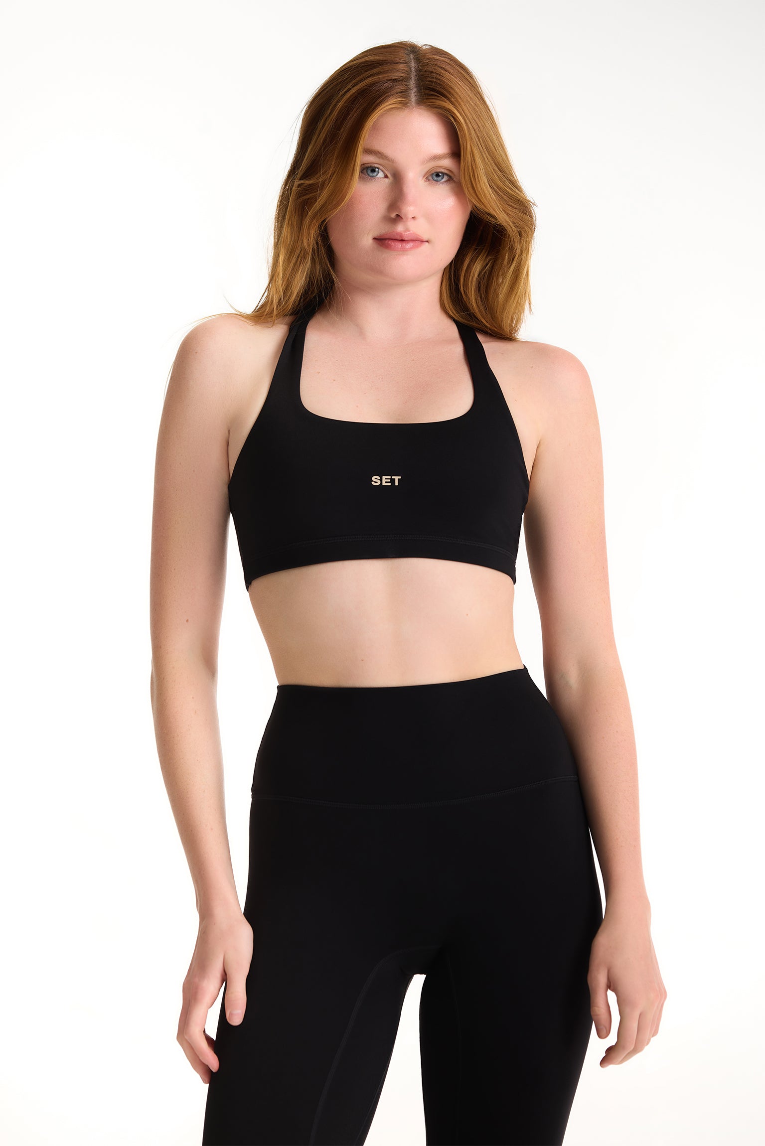 Woman wearing a black sports bra and leggings on a white background 