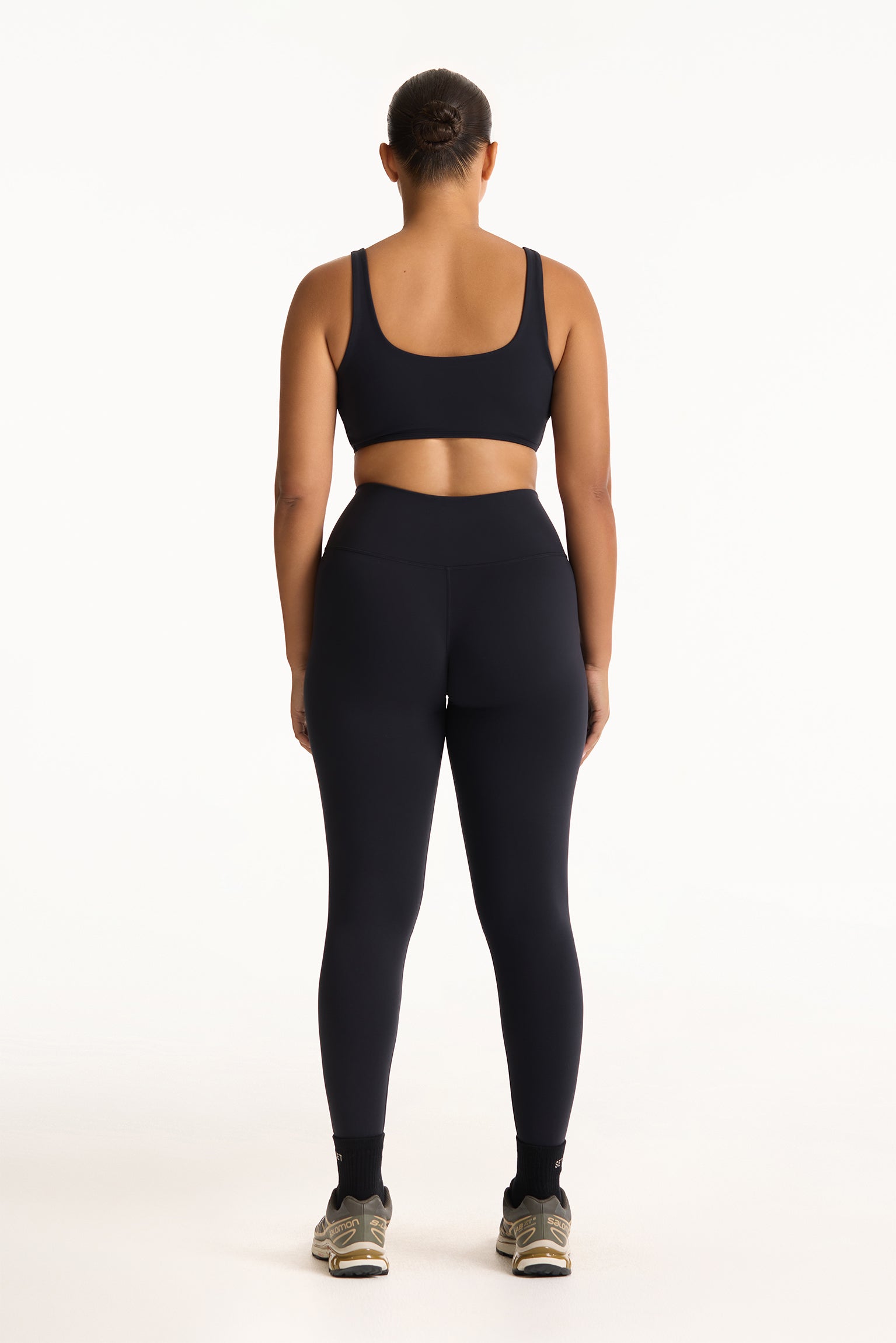 Person wearing a black sports bra and leggings set on a white background