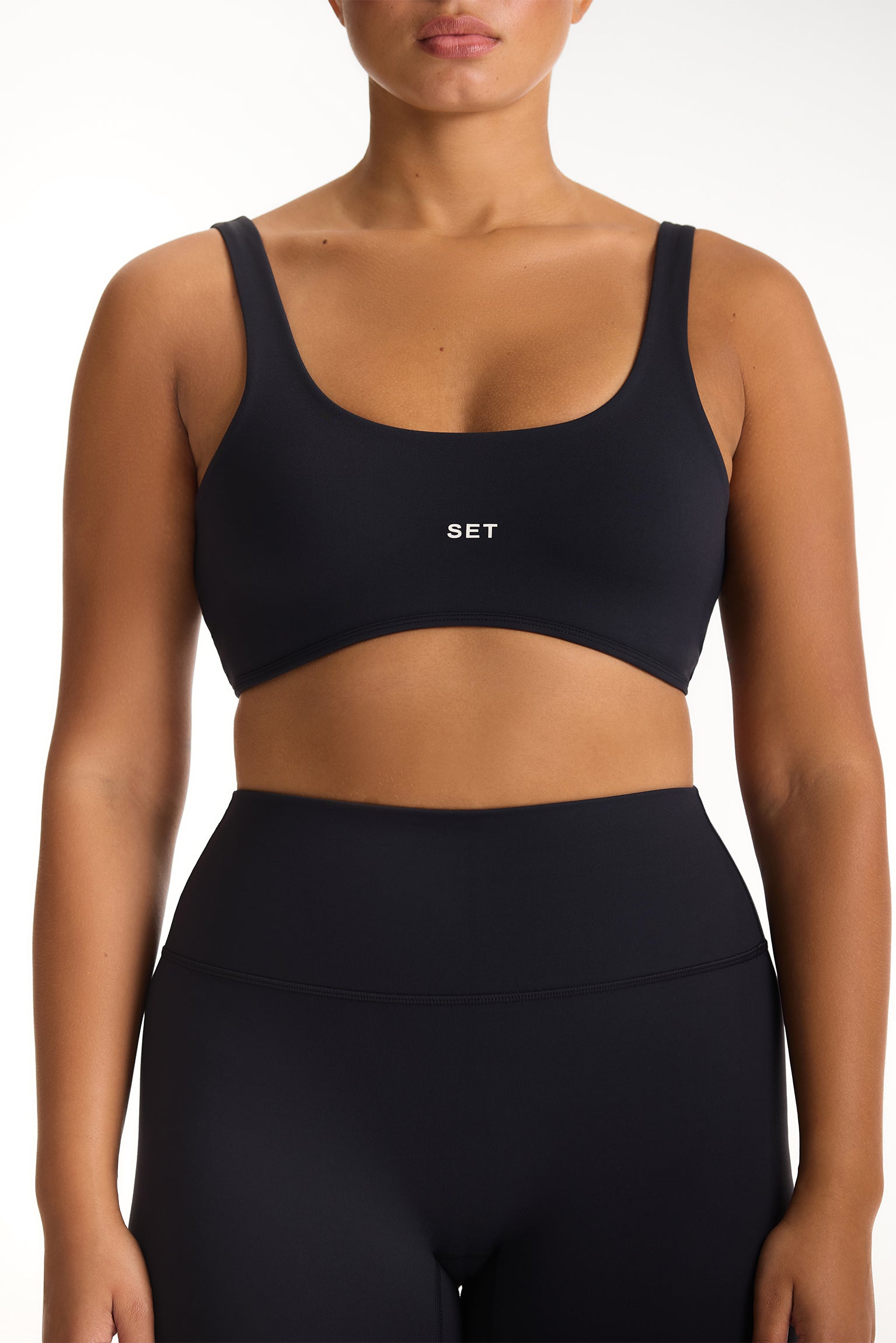 Person wearing a black sports bra and leggings with 'SET' branding on a white background