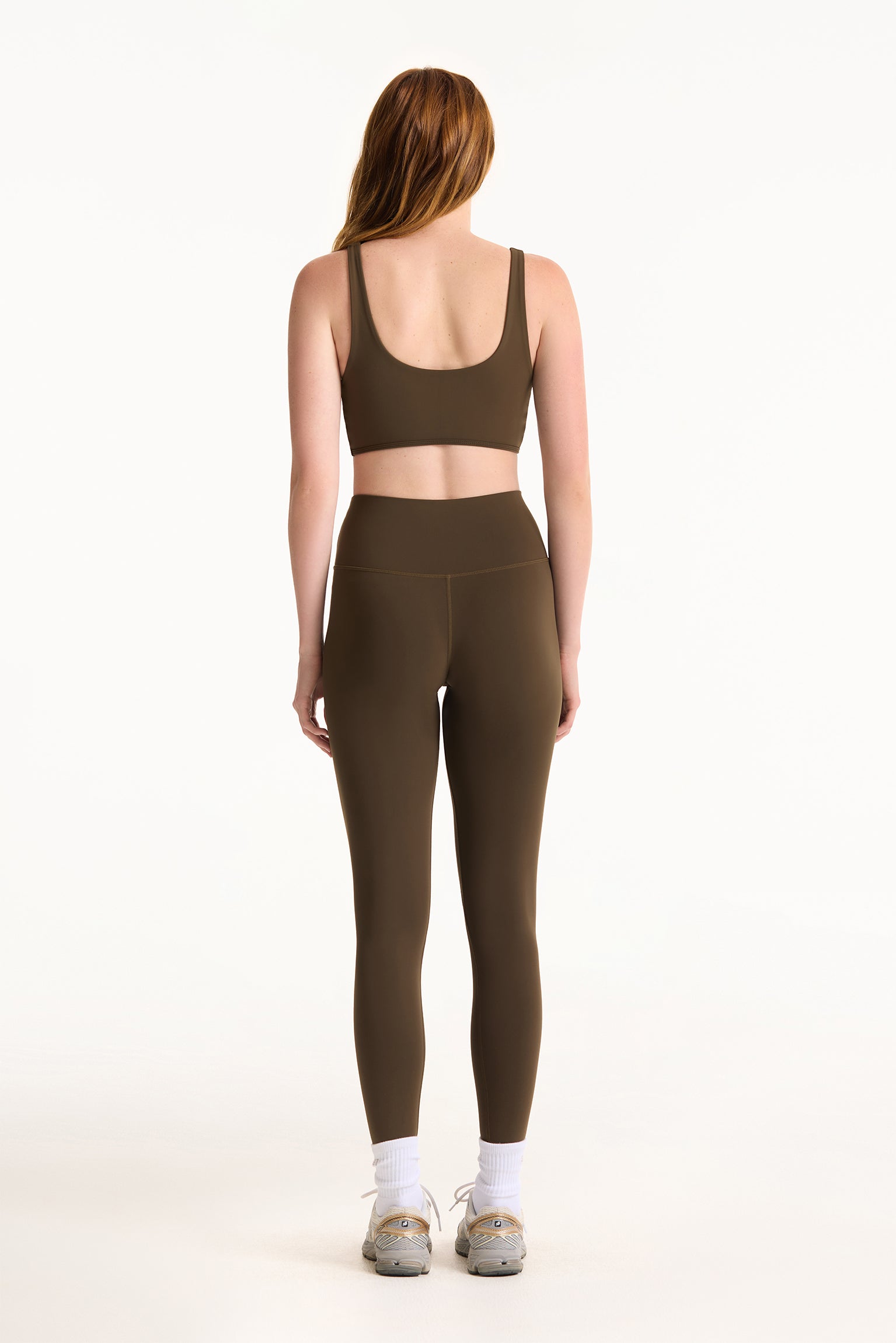 Person wearing a brown sports bra and leggings set on a white background