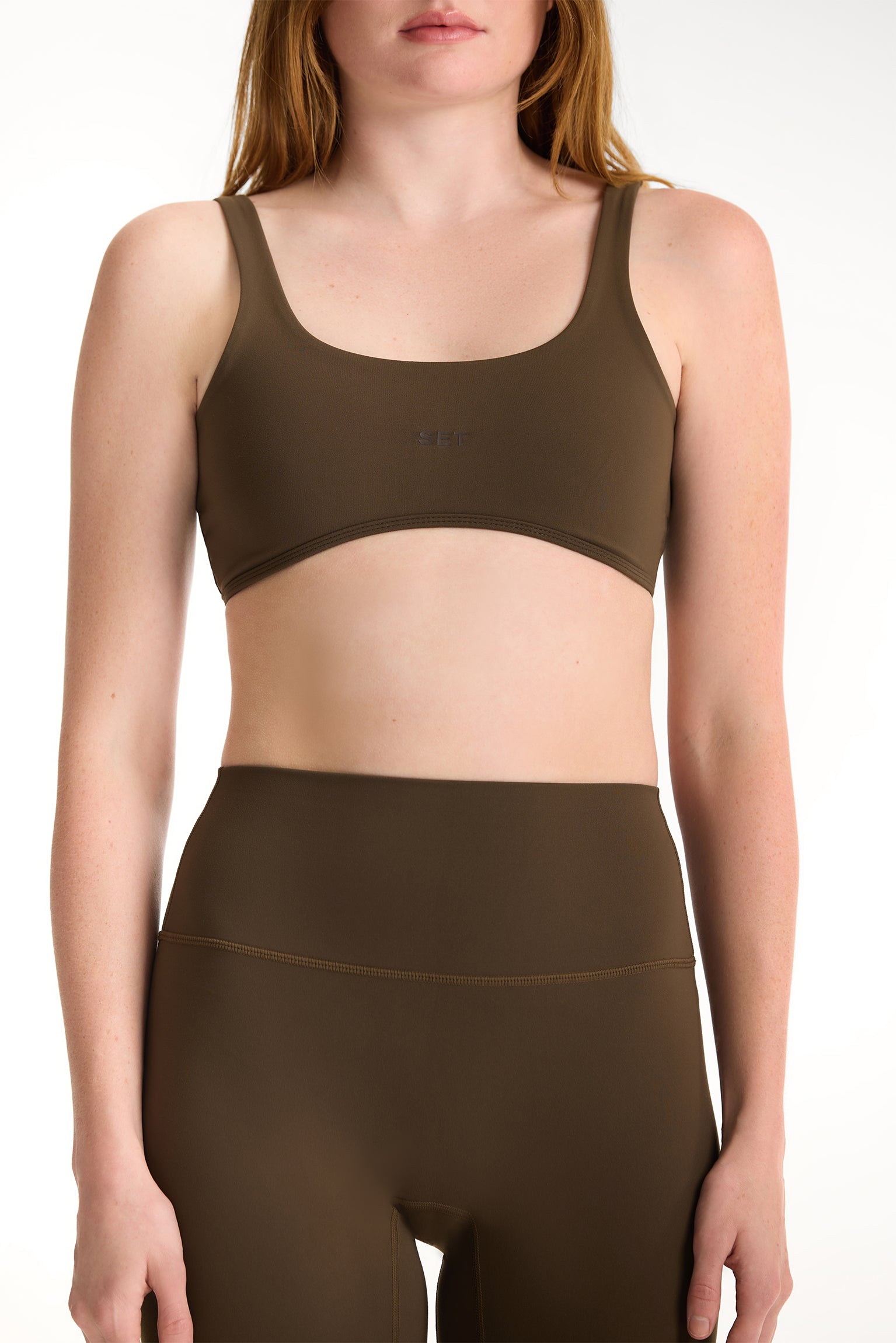 Person wearing a brown sports bra and leggings set on a white background