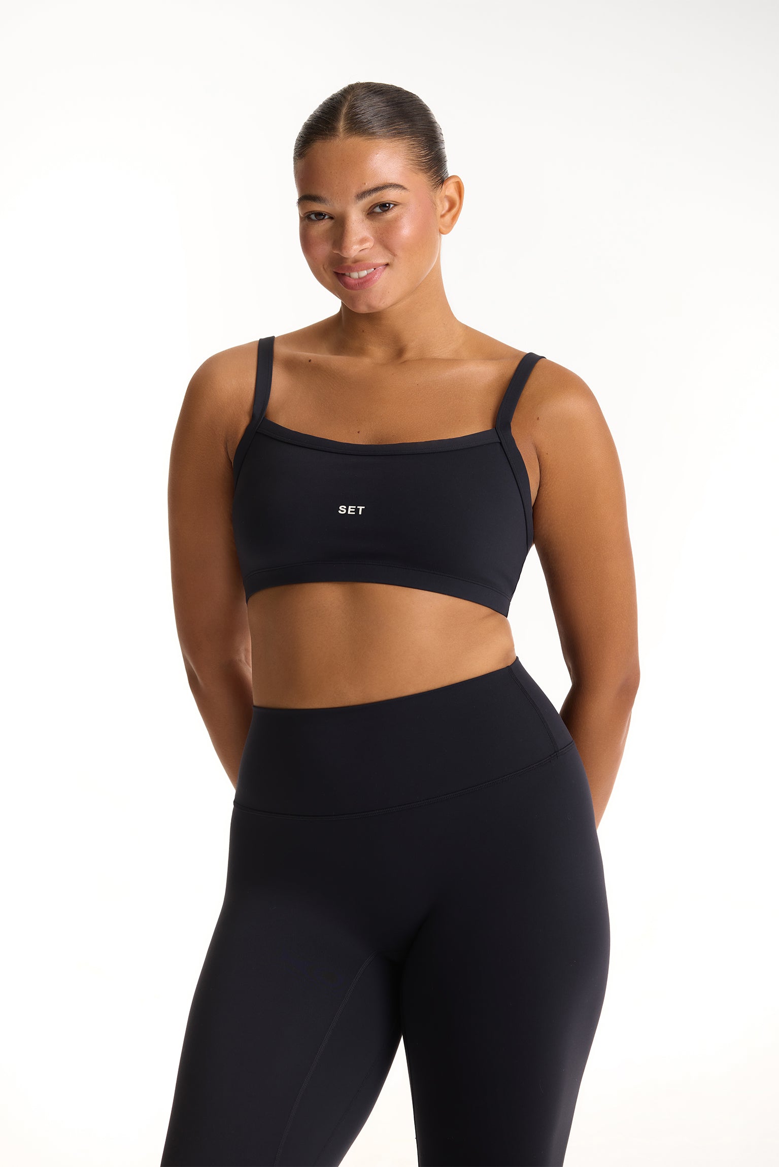 Woman wearing a black sports bra and leggings on a white background <model-info>Jade wears a size L and is 5’9”, 30” waist, 38” bust.</model-info>