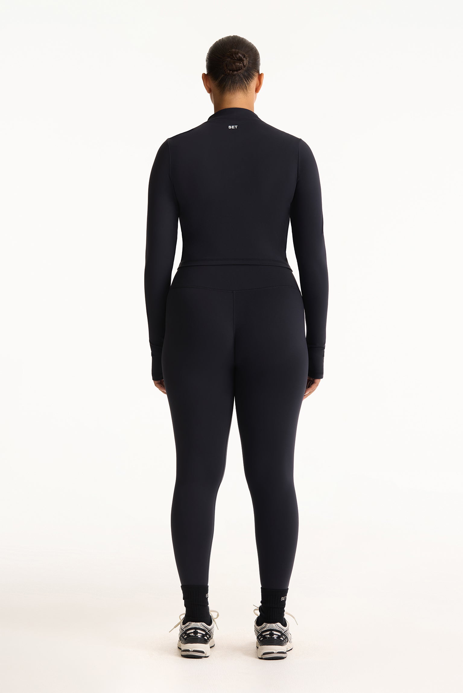 Person wearing a black full-body suit on a white background