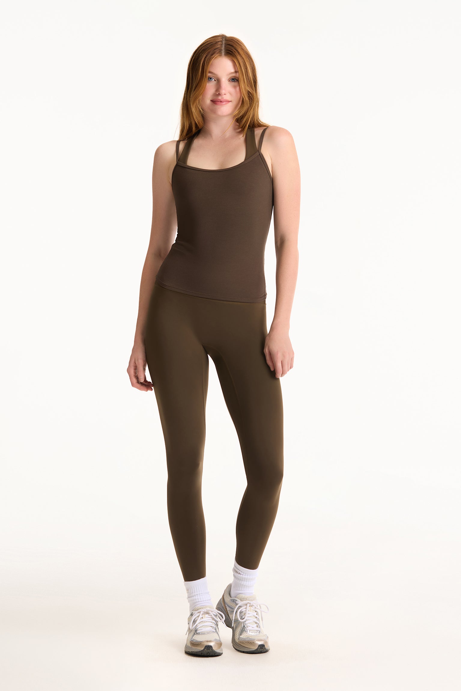 Woman wearing a brown tank top and leggings on a white background