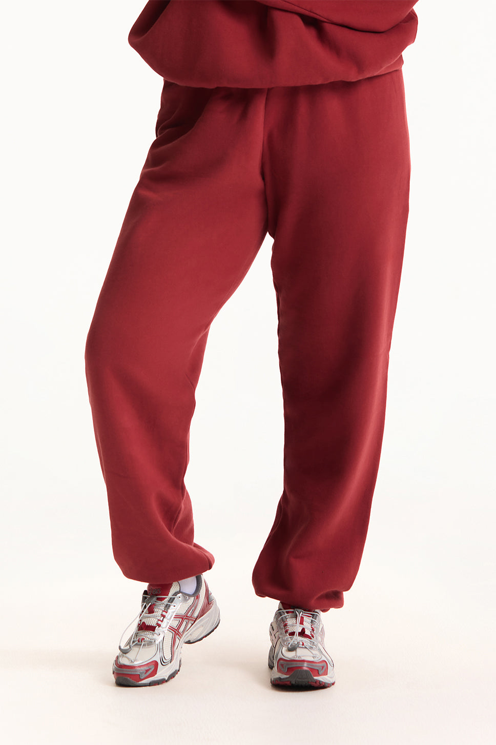 Red sweatpants worn with gray sneakers on a white background <model-info>Jade wears a size L and is 5’9”, 30” waist, 38” bust.</model-info>