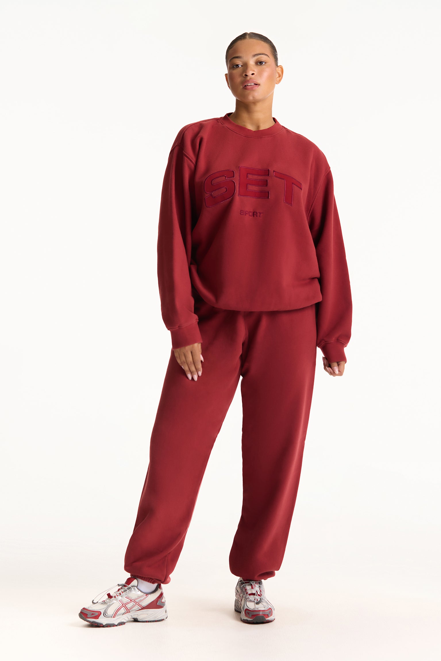 Person wearing a red tracksuit with 'SET' branding on a white background