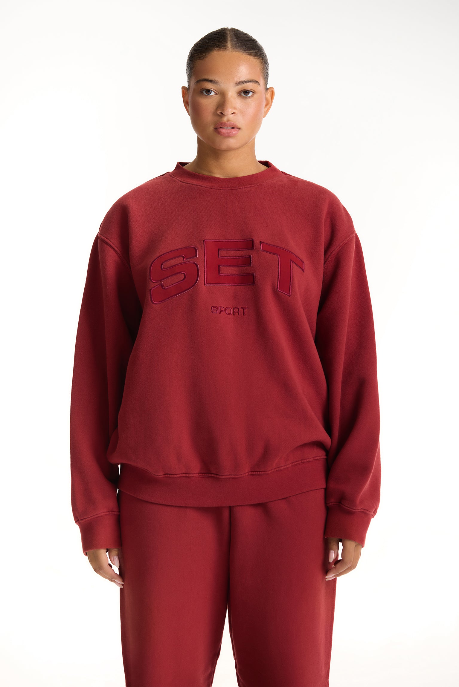 Person wearing a red 'SET' sweatshirt on a white background <model-info>Jade wears a size L and is 5’9”, 30” waist, 38” bust.</model-info>