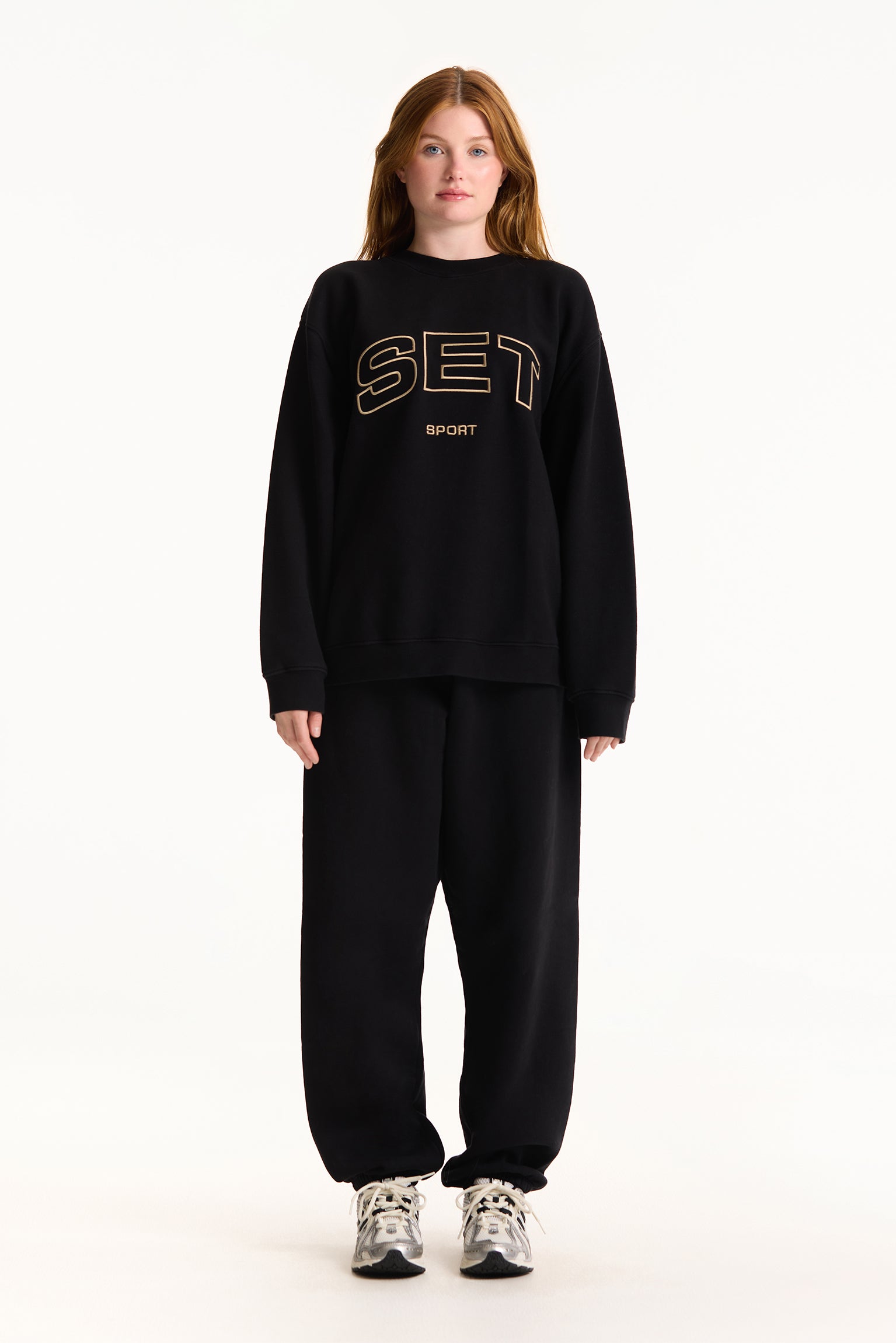 Person wearing a black sweatshirt with 'SET' logo on a white background
