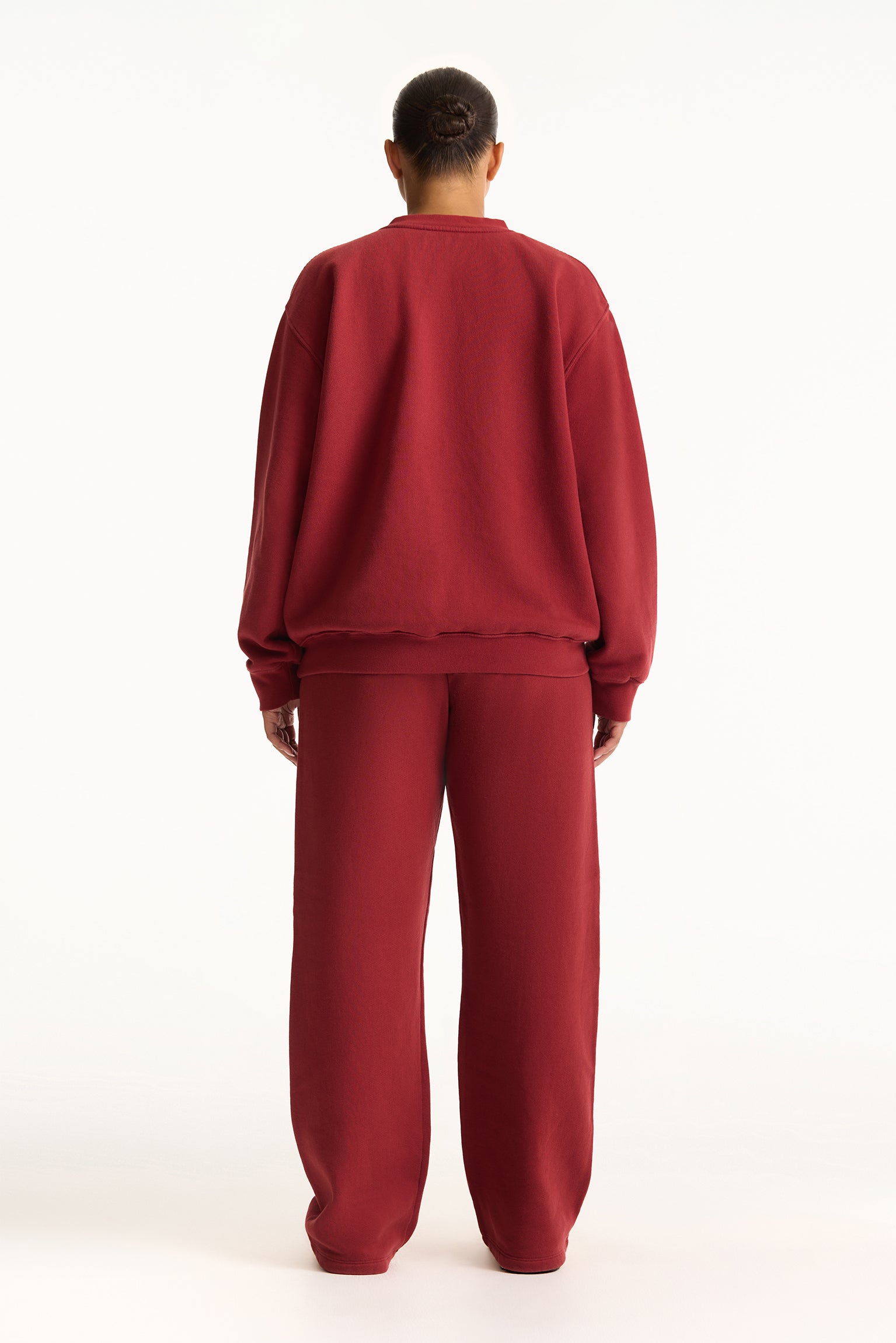 Person wearing a red sweatshirt and pants set on a white background