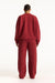 Person wearing a red sweatshirt and pants set on a white background