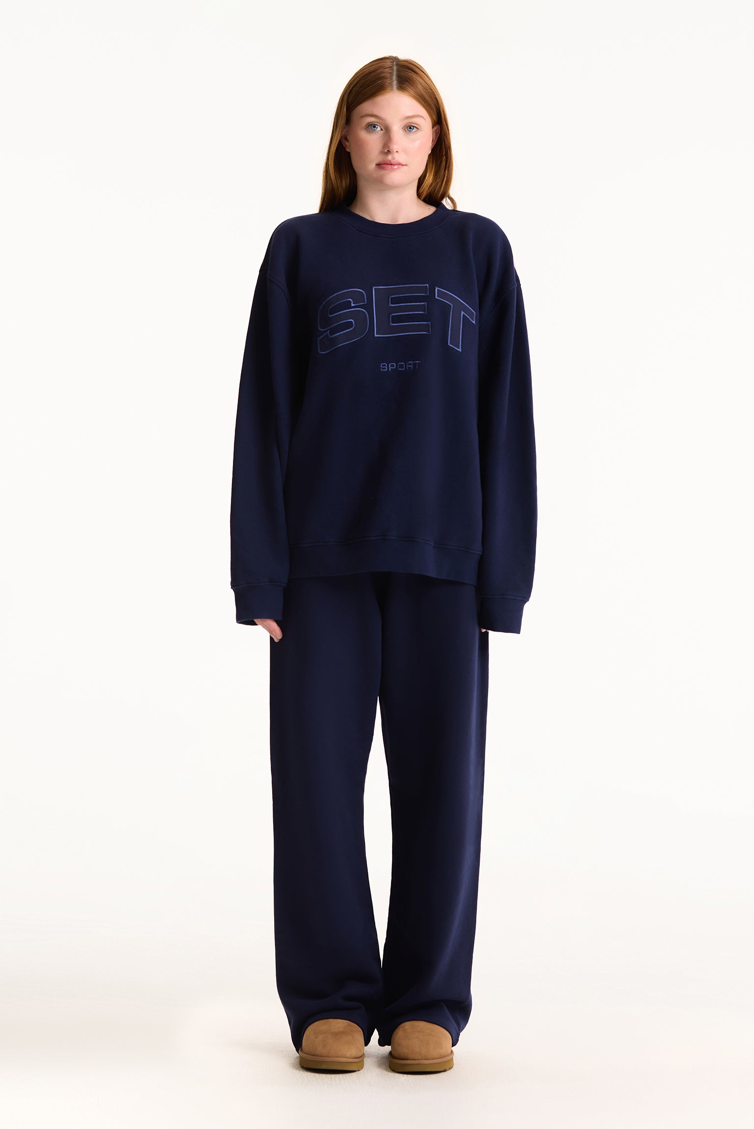 Person wearing a navy blue sweatshirt and pants with 'SET' logo on a white background