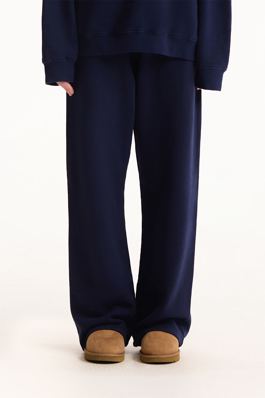Person wearing navy blue sweatpants and a matching top on a white background 