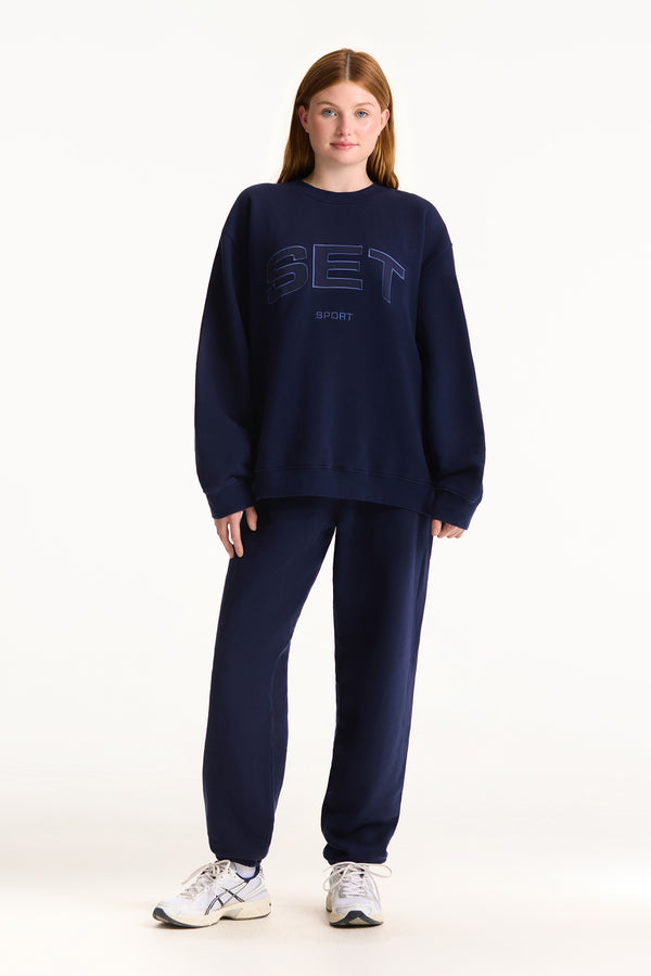 Person wearing a navy blue sweatshirt with 'BET' logo on a white background
