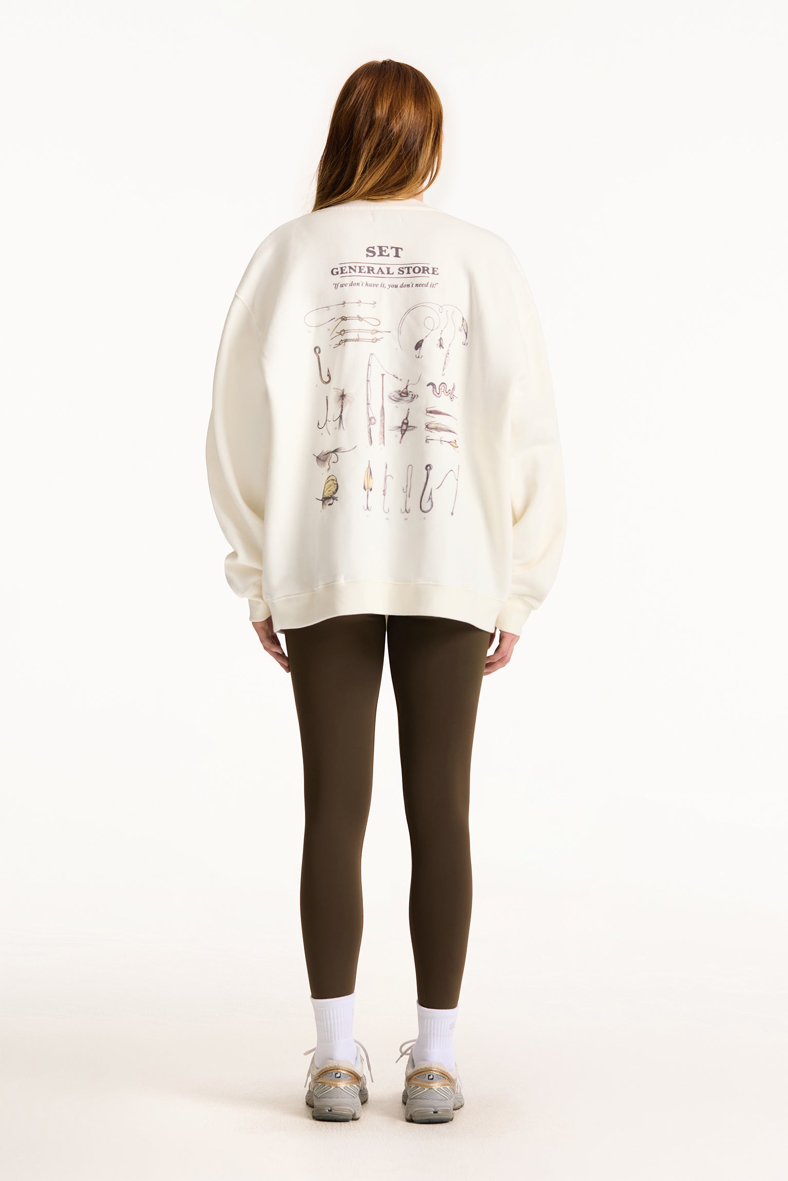 Person wearing a white sweatshirt with text and graphics on the back, standing against a white background.