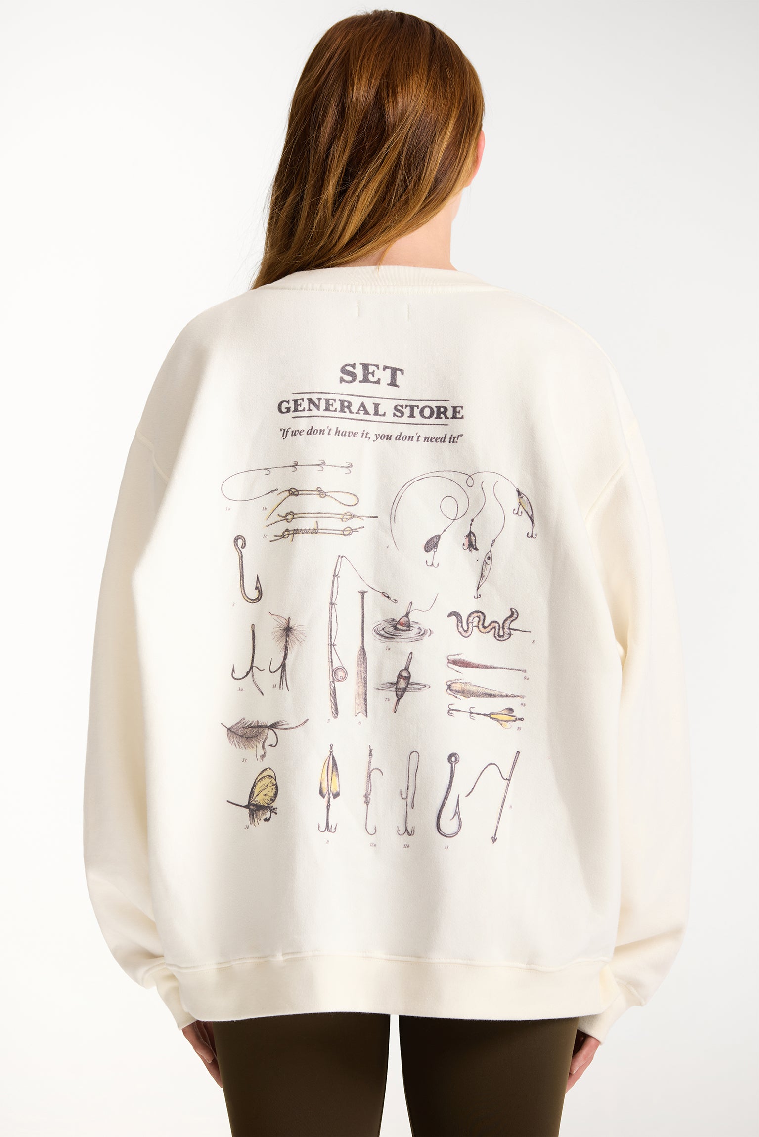 Person wearing a cream-colored sweatshirt with printed designs and text on the back.