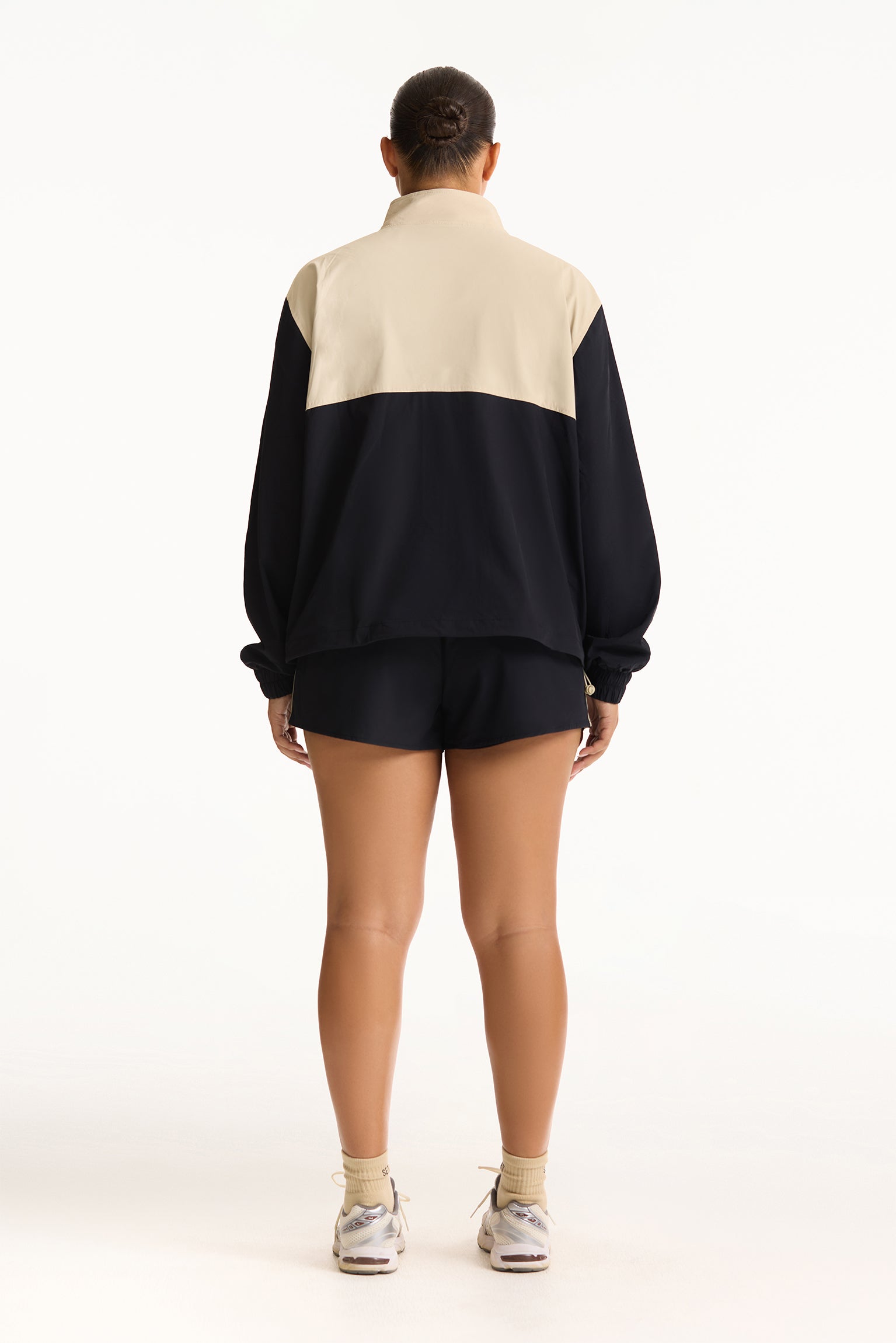 Person wearing a black and beige color-blocked outfit on a white background