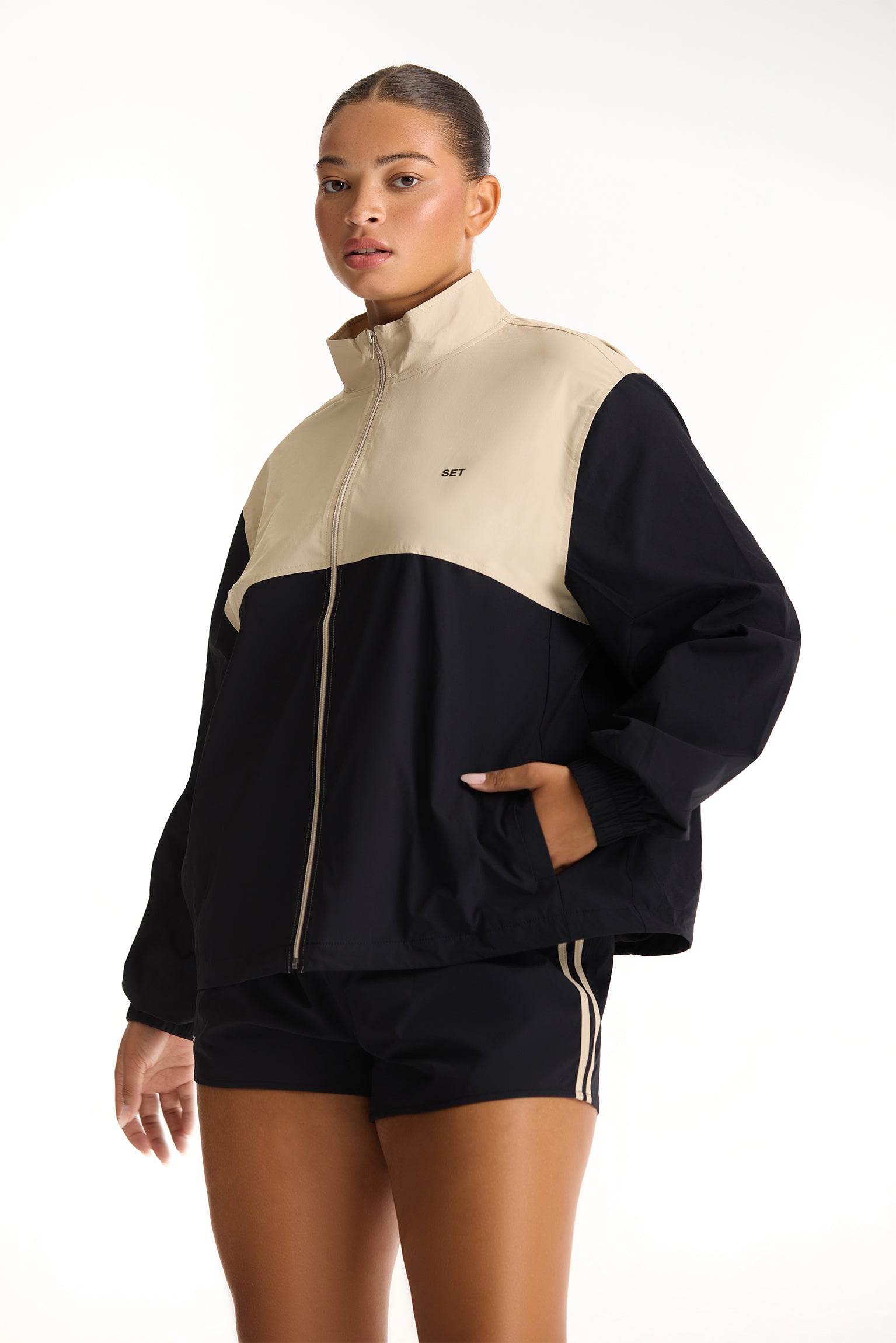 Woman wearing a black and beige tracksuit on a white background 