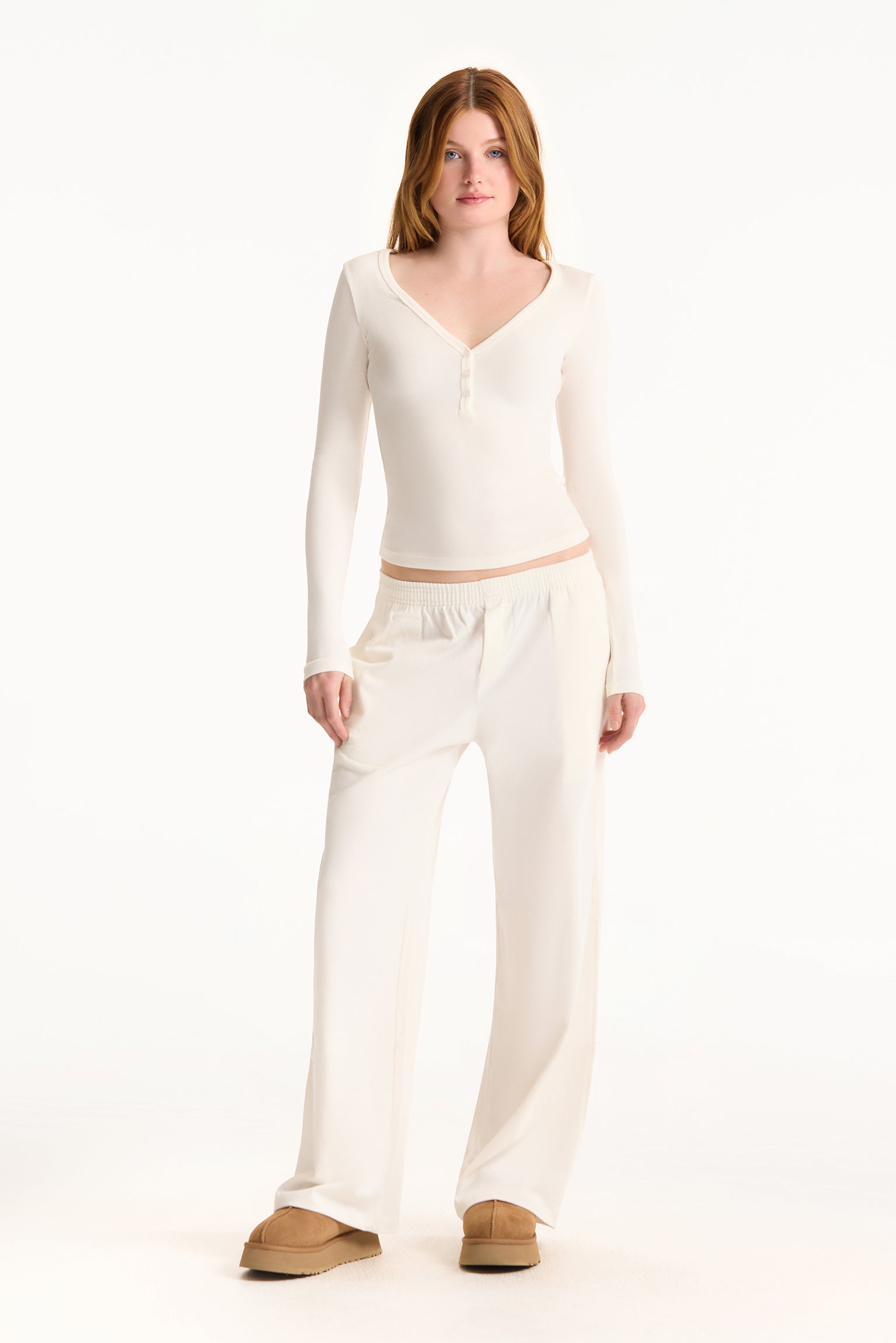 Woman wearing a white long-sleeve top and pants on a white background