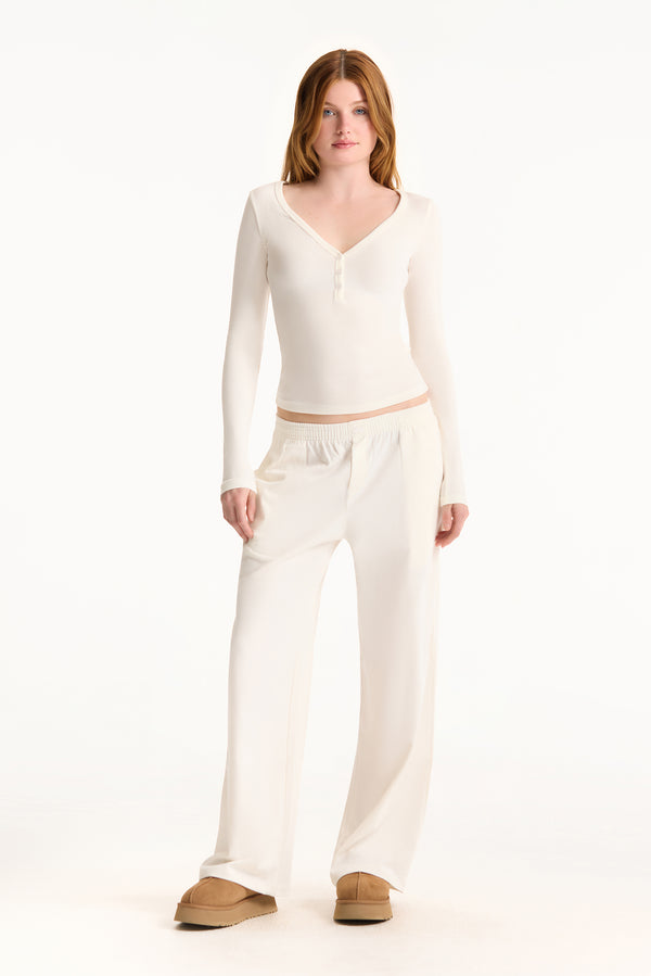 Woman wearing a white long-sleeve top and pants on a white background